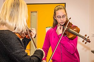 Musiklehrerin und jugendliche Schülerin stimmen gemeinsam ihre Violinen